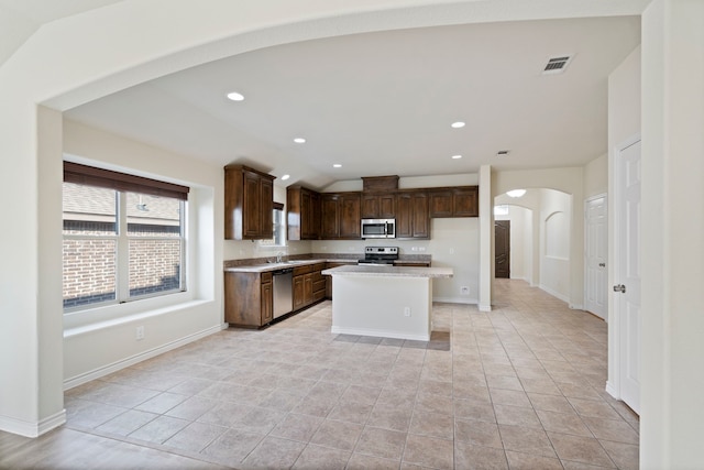 kitchen featuring arched walkways, recessed lighting, a sink, light countertops, and appliances with stainless steel finishes