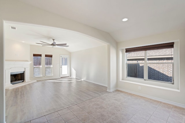 unfurnished living room featuring lofted ceiling, visible vents, plenty of natural light, and a fireplace with raised hearth