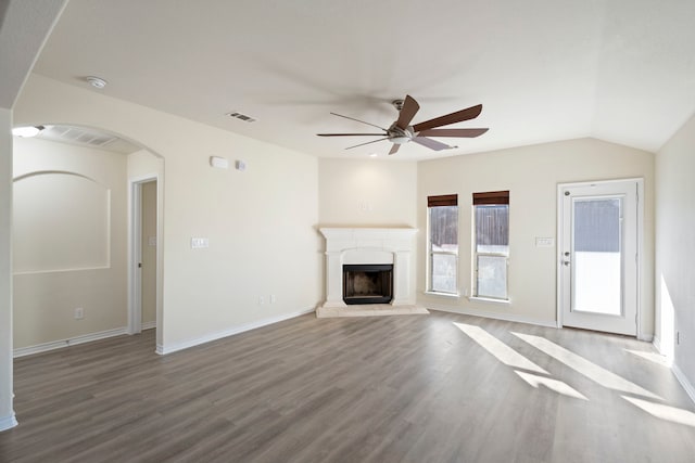 unfurnished living room with ceiling fan, visible vents, a fireplace with raised hearth, and wood finished floors