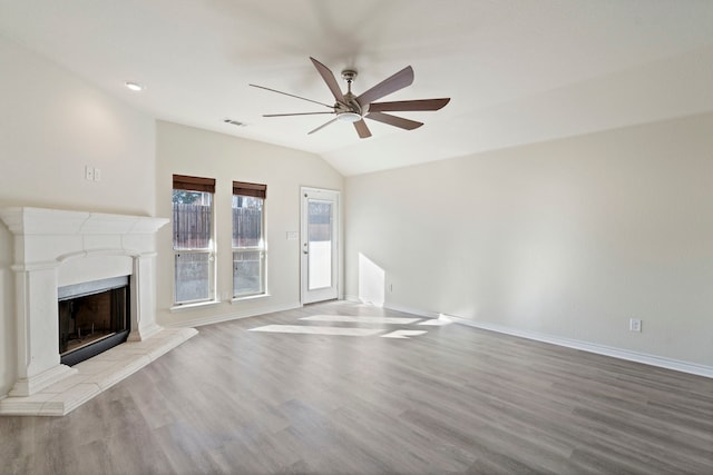 unfurnished living room featuring a fireplace with raised hearth, wood finished floors, visible vents, and baseboards