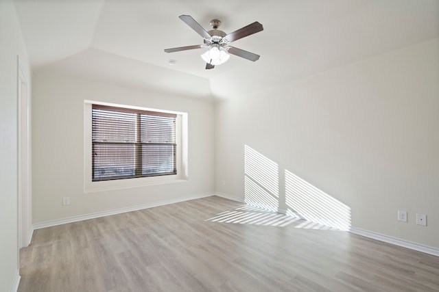 empty room with lofted ceiling, light wood finished floors, and baseboards