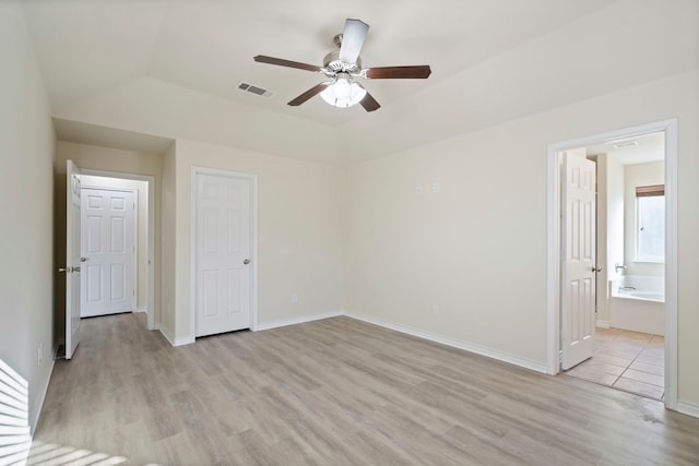 unfurnished bedroom with light wood finished floors, visible vents, connected bathroom, ceiling fan, and baseboards