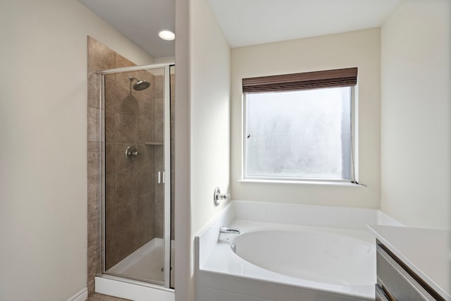 bathroom with a healthy amount of sunlight, a stall shower, a bath, and vanity