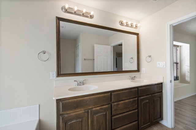 full bath with wood finished floors, a sink, baseboards, and double vanity