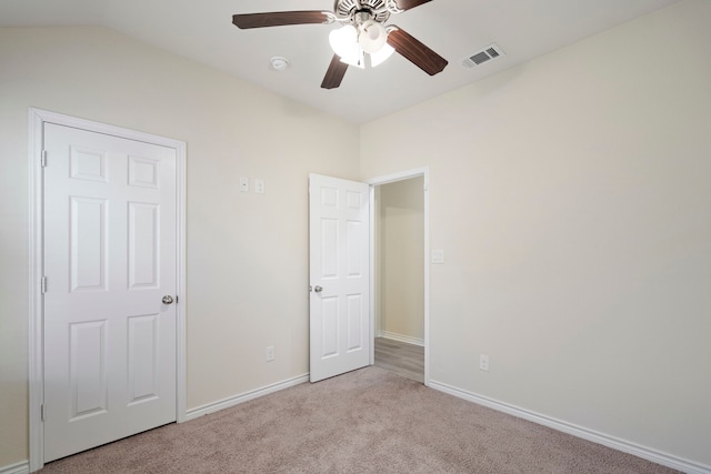 unfurnished bedroom with ceiling fan, lofted ceiling, visible vents, baseboards, and carpet