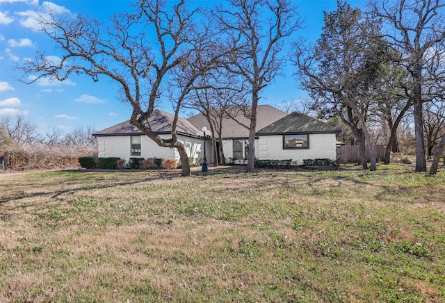 single story home featuring a front yard, brick siding, and fence