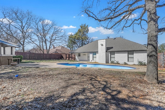 rear view of house with brick siding, fence, a fenced in pool, and a patio