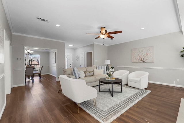 living area featuring baseboards, visible vents, dark wood-style floors, ornamental molding, and ceiling fan with notable chandelier