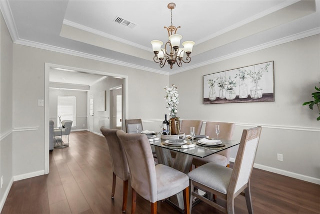 dining room with an inviting chandelier, visible vents, dark wood finished floors, and a raised ceiling