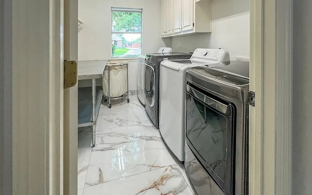 clothes washing area featuring marble finish floor, washing machine and dryer, and cabinet space