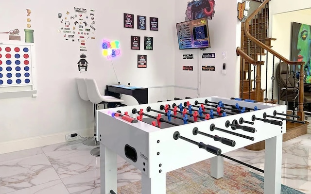 recreation room featuring marble finish floor and baseboards