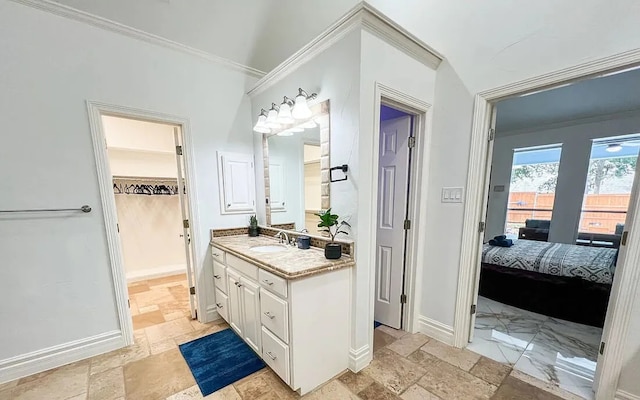 ensuite bathroom featuring baseboards, vanity, stone tile flooring, and crown molding