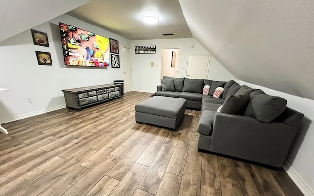 living room with vaulted ceiling, wood finished floors, visible vents, and baseboards