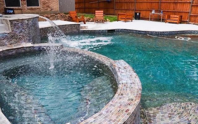 view of swimming pool featuring a jacuzzi and fence