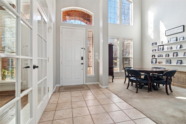 entrance foyer featuring a healthy amount of sunlight, light colored carpet, french doors, and light tile patterned flooring