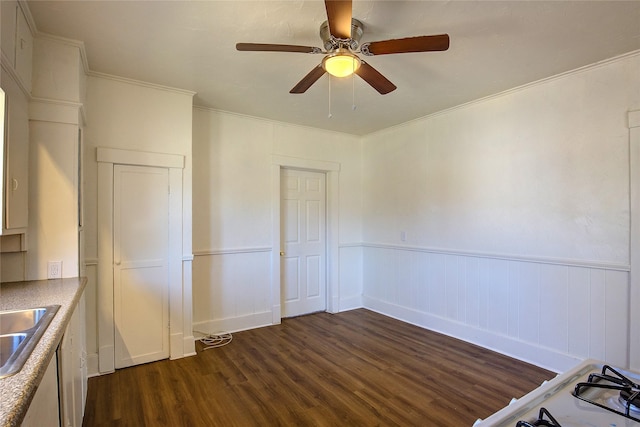 unfurnished bedroom featuring wainscoting, ceiling fan, ornamental molding, dark wood-style flooring, and a sink