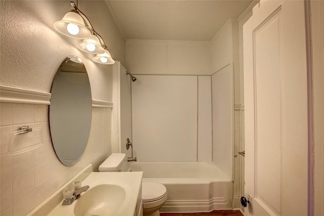 full bathroom with tile walls, bathing tub / shower combination, toilet, wainscoting, and vanity