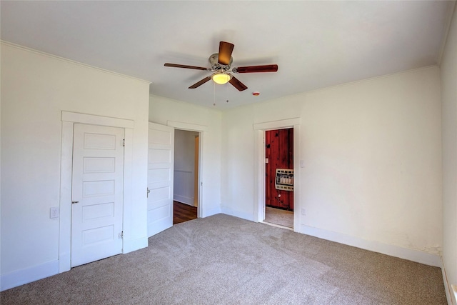 unfurnished bedroom with carpet flooring, a ceiling fan, baseboards, heating unit, and crown molding