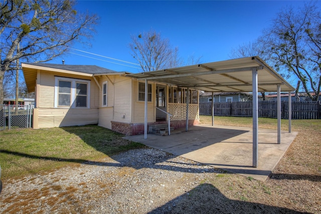 view of front of house featuring a carport, a front lawn, fence, and dirt driveway