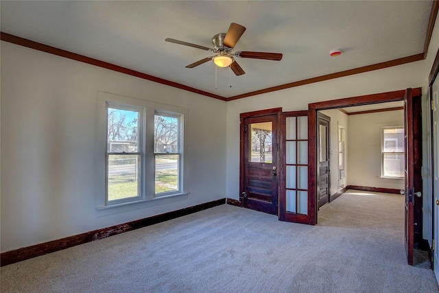 carpeted spare room featuring ceiling fan, french doors, ornamental molding, and baseboards