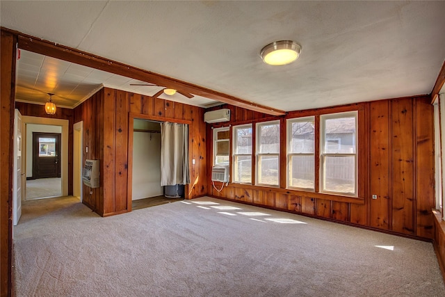 empty room featuring carpet, heating unit, a wall mounted AC, wood walls, and cooling unit