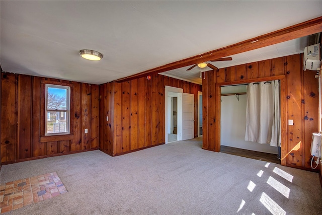 carpeted empty room featuring a ceiling fan and wooden walls