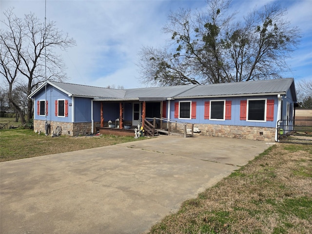 ranch-style house with a porch, metal roof, driveway, and a front lawn