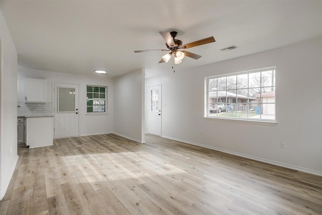 unfurnished room featuring light wood finished floors, baseboards, visible vents, and ceiling fan