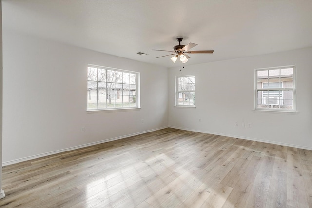 spare room featuring light wood-type flooring, visible vents, and baseboards