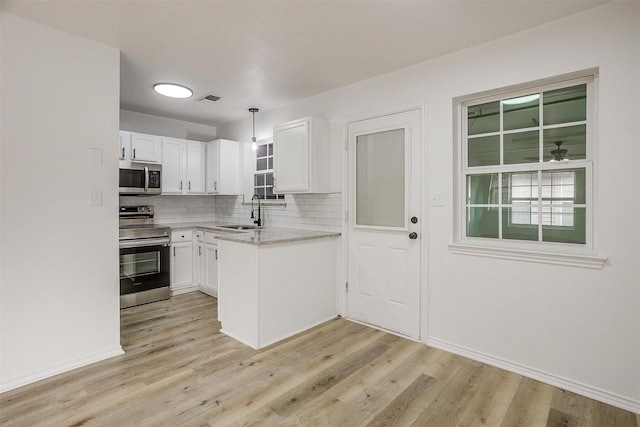 kitchen featuring visible vents, a sink, stainless steel appliances, white cabinetry, and backsplash