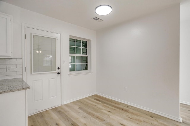 doorway featuring baseboards, visible vents, and light wood-style floors