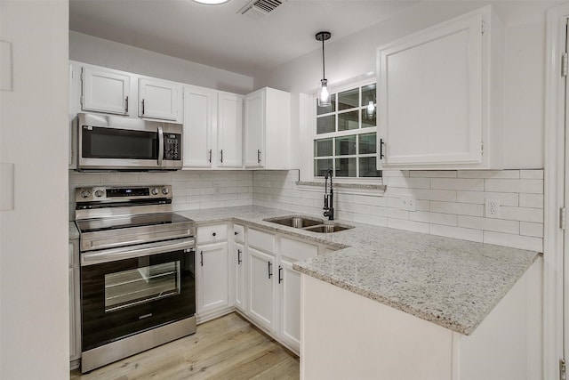 kitchen featuring stainless steel appliances, tasteful backsplash, visible vents, white cabinetry, and a sink