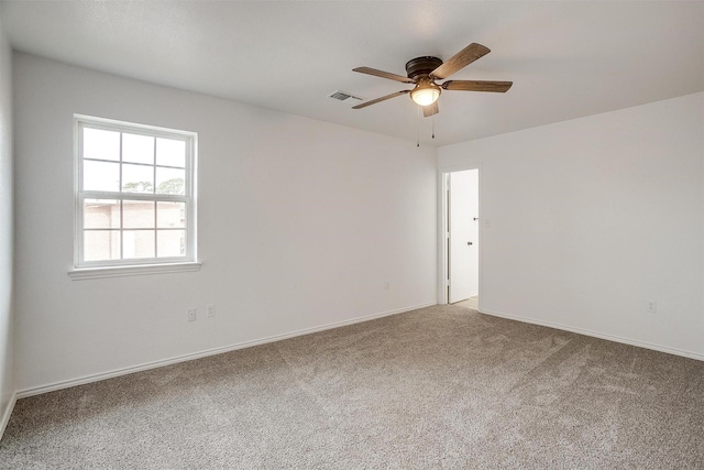 unfurnished room with carpet, visible vents, ceiling fan, and baseboards