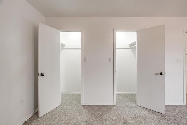 unfurnished bedroom with a closet, carpet, a walk in closet, and baseboards