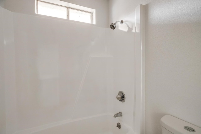 bathroom featuring tub / shower combination and toilet