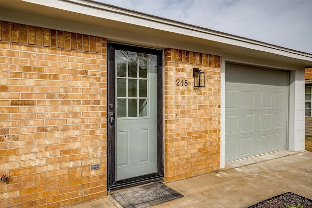 property entrance featuring a garage and brick siding