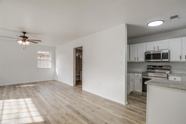 kitchen featuring light wood finished floors, tasteful backsplash, visible vents, and stainless steel appliances