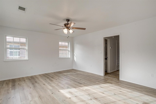 spare room with baseboards, light wood-type flooring, visible vents, and a ceiling fan