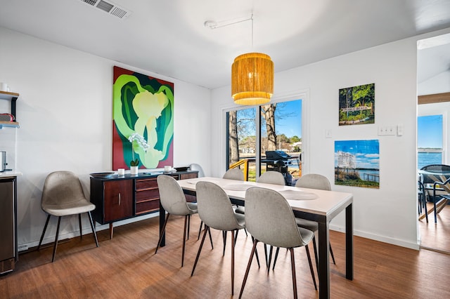 dining space featuring wood finished floors, visible vents, and baseboards