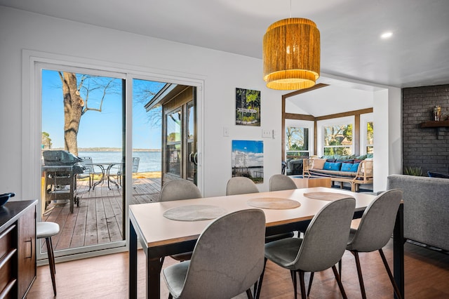 dining room with a water view, a brick fireplace, plenty of natural light, and wood finished floors