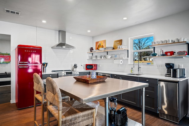 kitchen featuring a sink, visible vents, wall chimney range hood, freestanding refrigerator, and open shelves