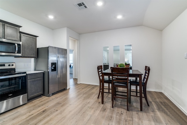 kitchen featuring light wood finished floors, visible vents, appliances with stainless steel finishes, vaulted ceiling, and light countertops