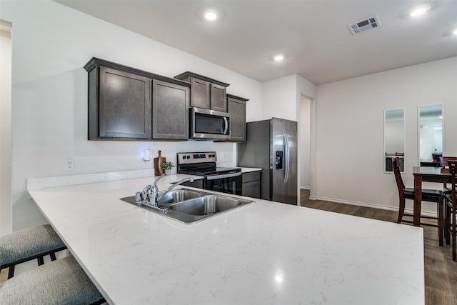 kitchen featuring dark wood finished floors, visible vents, appliances with stainless steel finishes, a sink, and dark brown cabinets