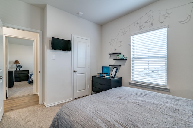 bedroom featuring light carpet and baseboards