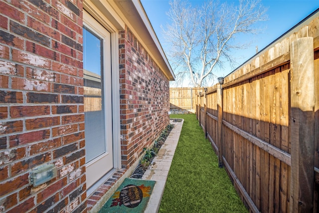 view of side of property featuring brick siding and fence