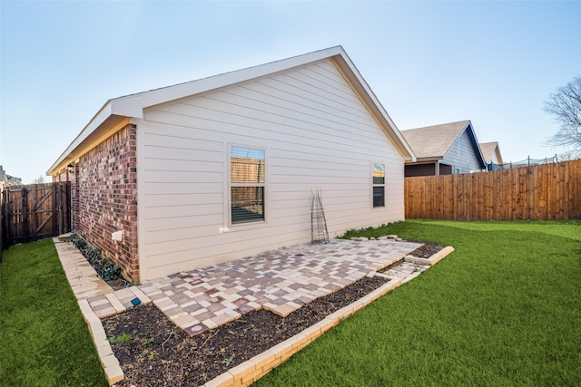 back of house with a yard, brick siding, a patio, and a fenced backyard