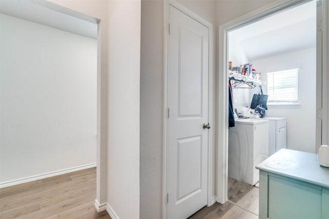 interior space with washer and dryer, laundry area, baseboards, and light wood finished floors