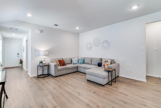 living area featuring lofted ceiling, visible vents, light wood-style flooring, and recessed lighting