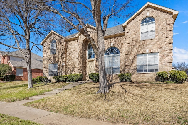 traditional-style home featuring a front lawn and brick siding