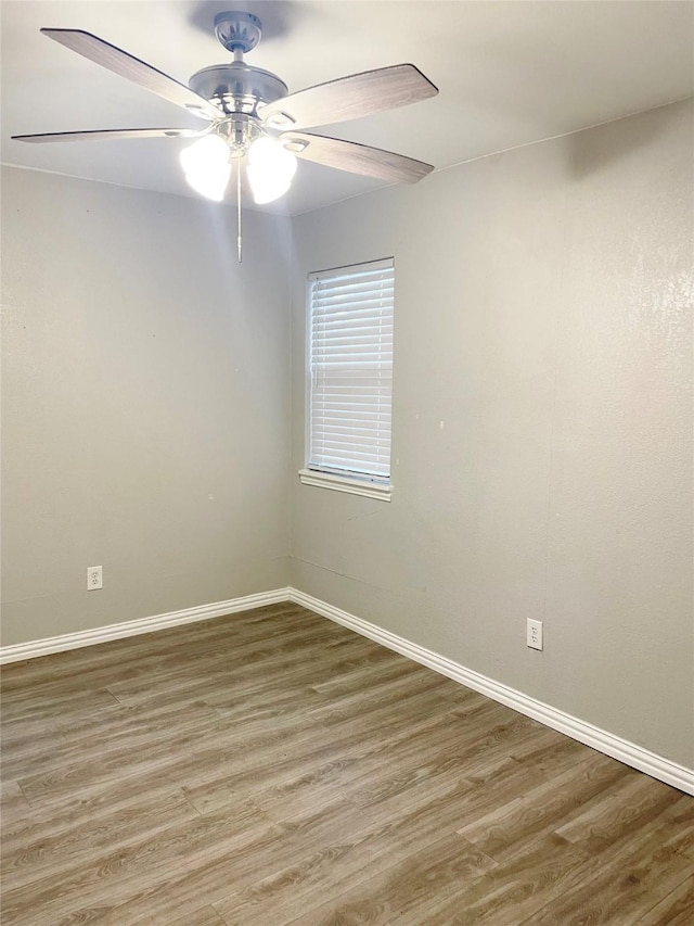 empty room featuring a ceiling fan, baseboards, and wood finished floors